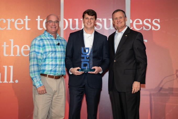 Andrew Swint (center) accepting his award at DHGs annual partner meeting in Orlando.