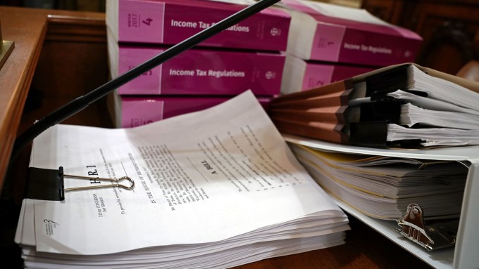 A printout of Congress's tax reform bill, The Tax Cuts and Jobs Act, alongside a stack of income tax regulations