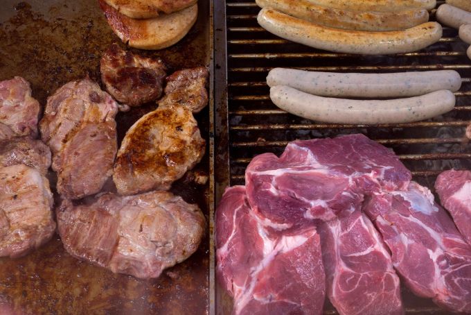 Pork and red meat cook on a griddle at a butcher's market stall in Berlin.